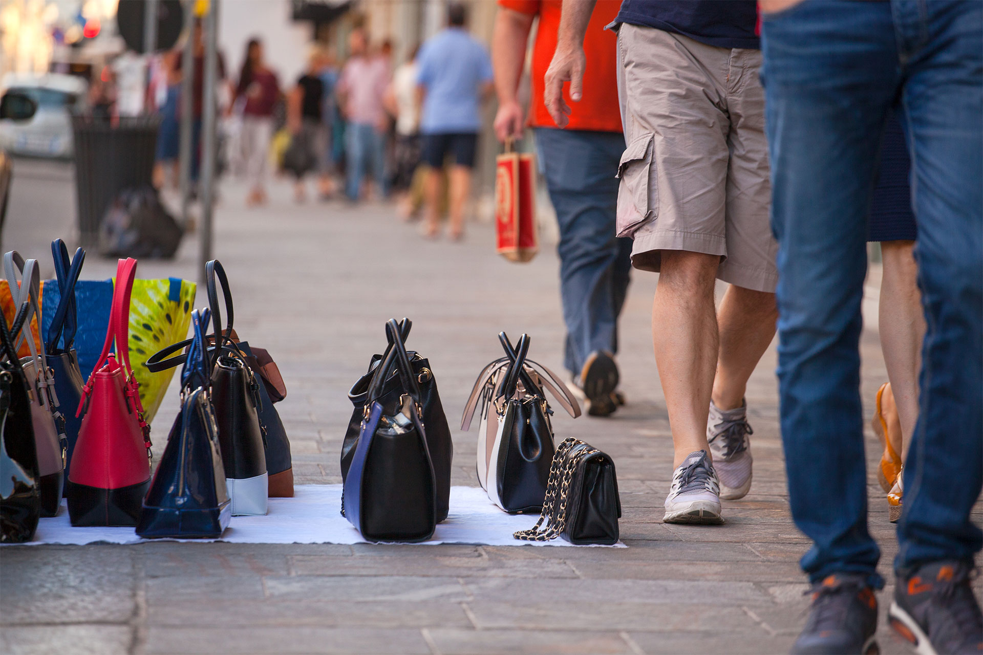 Borse contraffatte dei marocchini lungo la strada con persone che camminano vicino