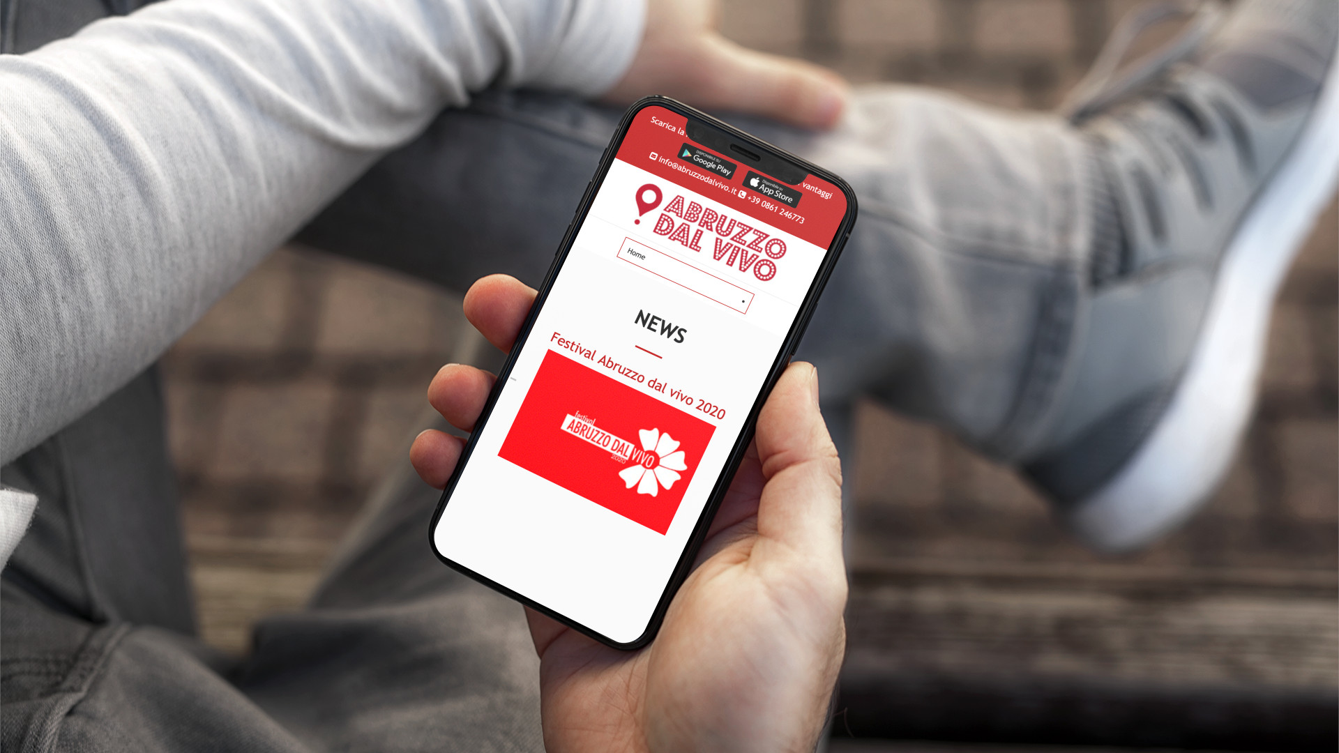 Mano con iPhone che mostra il sito web in modalità mobile responsive di Abruzzo Dal Vivo