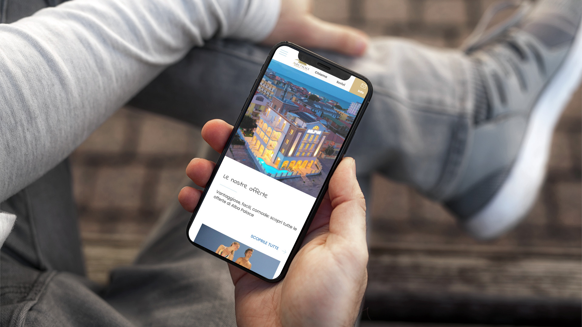 Mano con iPhone che mostra il sito web in modalità mobile responsive di Alba Palace di Alba Adriatica