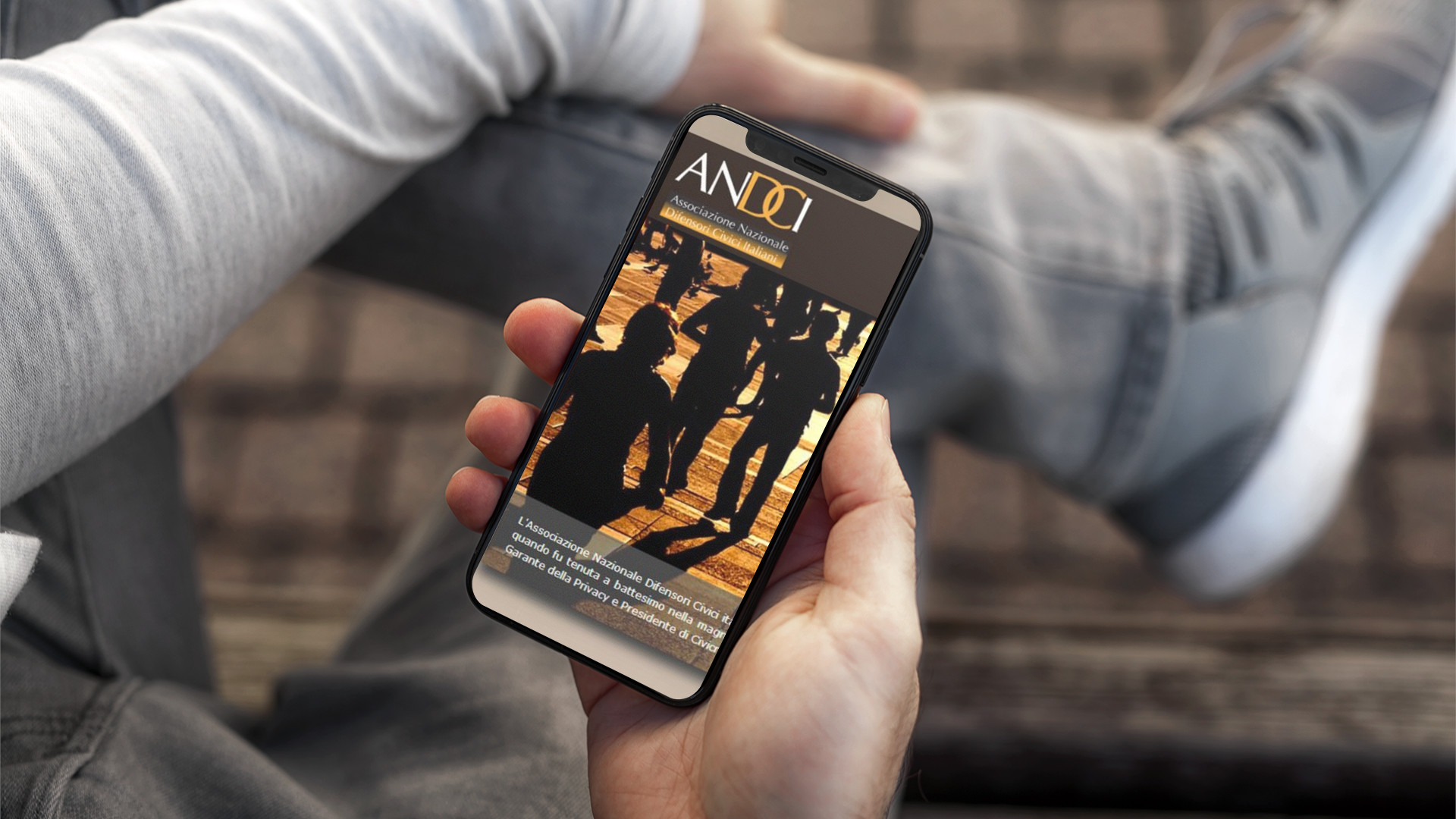 Mano con iPhone che mostra il sito web in modalità mobile responsive di ANDCI di Roma