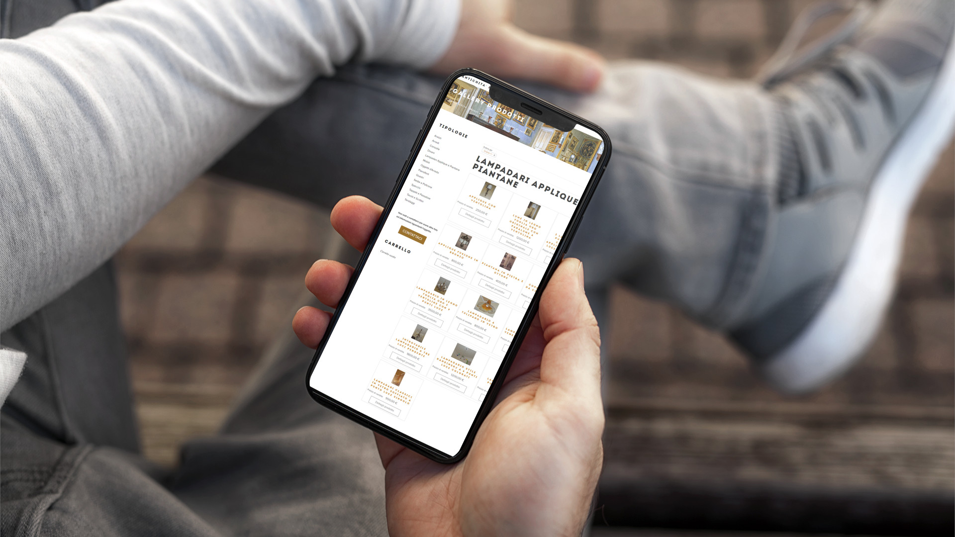 Mano con iPhone che mostra il sito web in modalità mobile di Antichità Preziose di Teramo