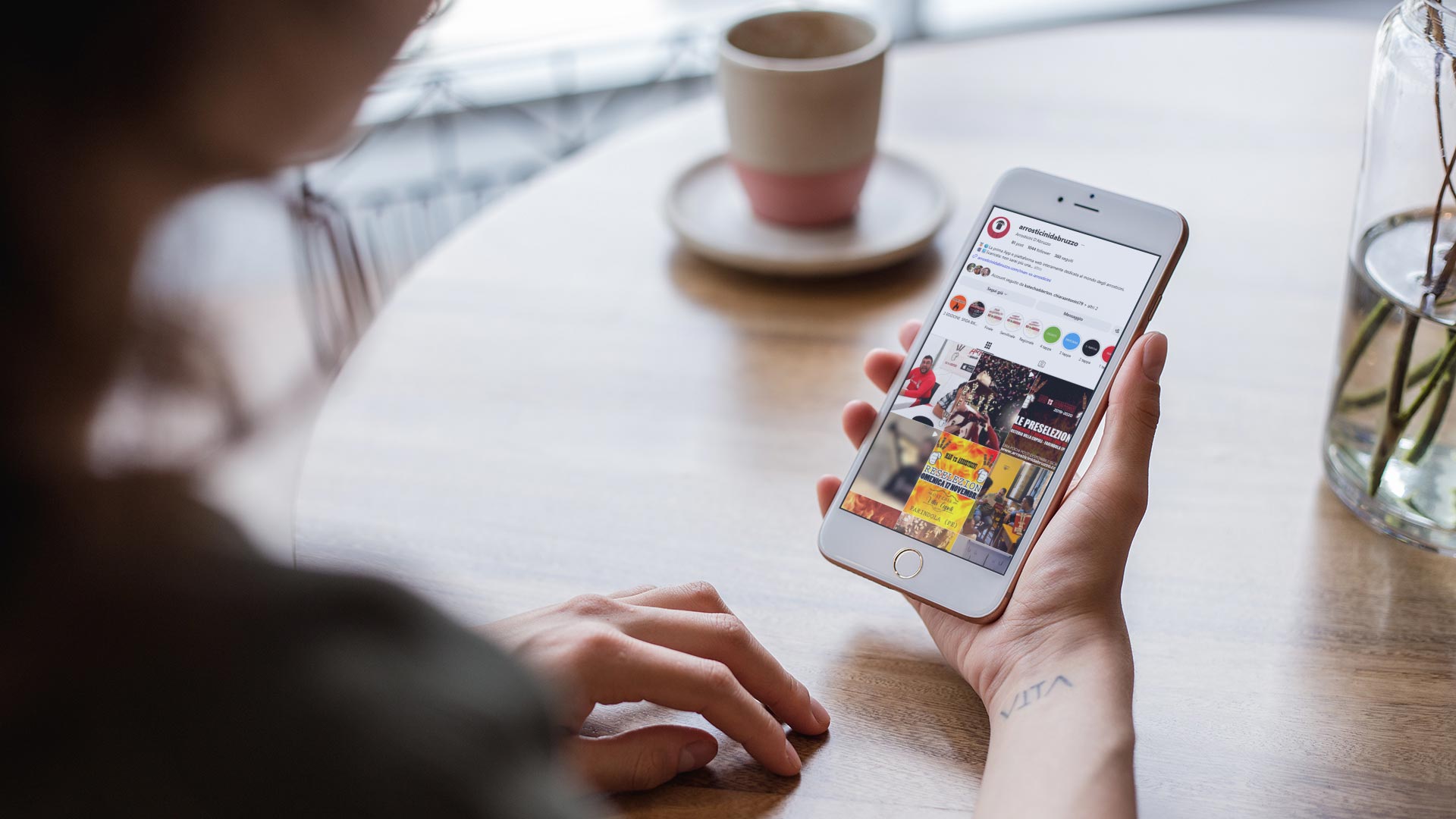 Donna consulta il feed Instagram di Arrosticini d'Abruzzo davanti a un caffè