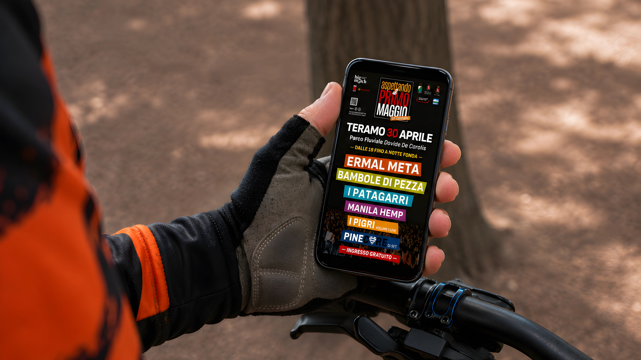 Ragazzo in bicicletta consulta sullo smartphone il sito di Aspettando il Primo Maggio