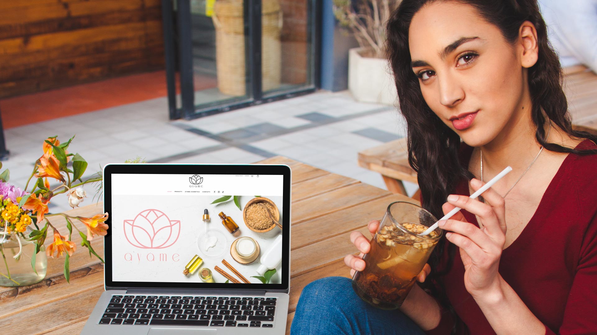 Ragazza con tisana davanti al computer che visualizza la home page del Sito Web E-Commerce Ayame Cosmetics
