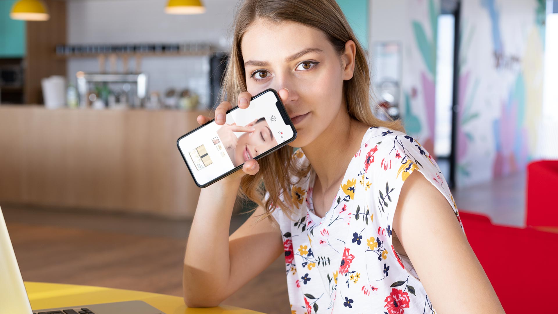 Ragazza in cucina che mostra su smartphone la scheda prodotto del Sito Web E-Commerce Ayame Cosmetics