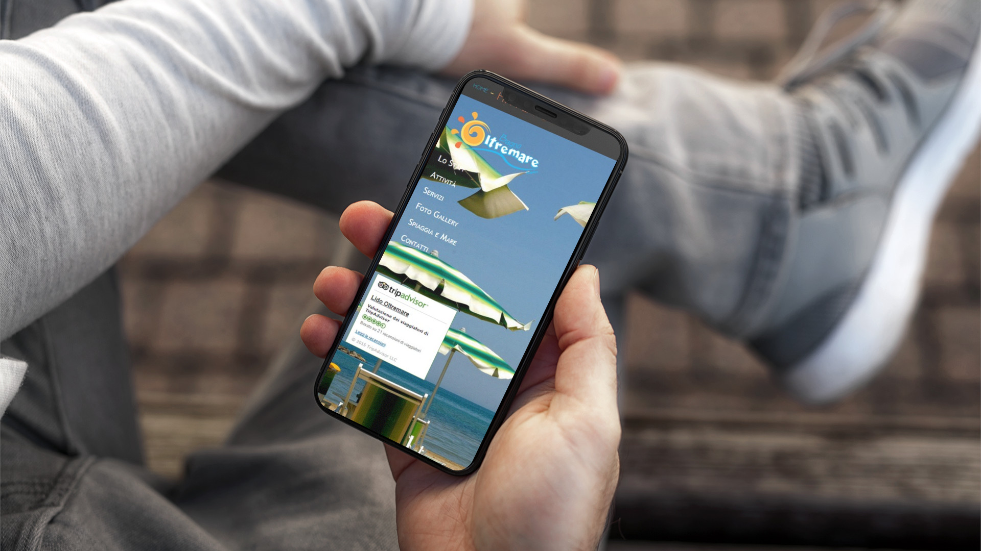 Mano con iPhone che mostra il sito web in modalità mobile di Bagno Oltremare di Roseto Degli Abruzzi