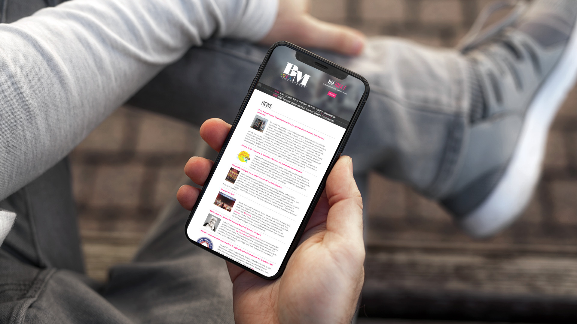 Mano con iPhone che mostra il sito web in modalità mobile responsive di BM Idea di Teramo