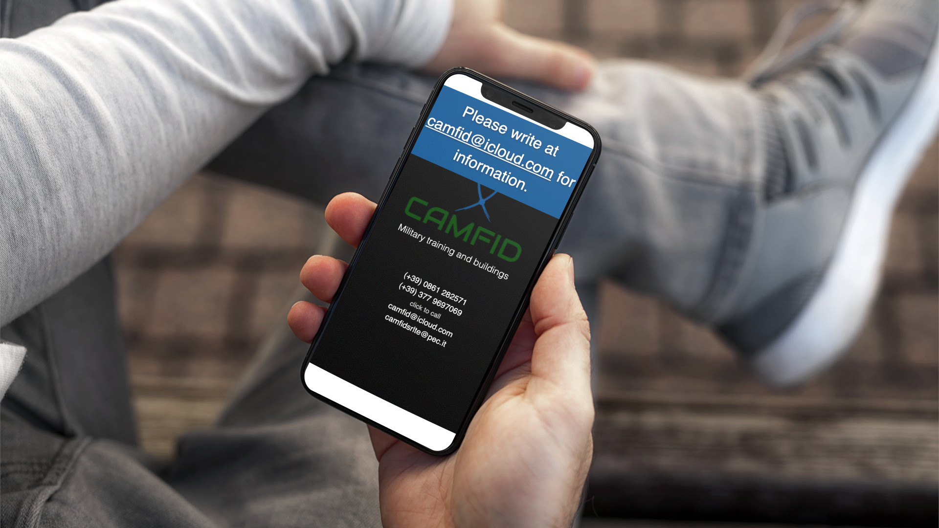 Mano con iPhone che mostra il sito web in modalità mobile responsive di CamFid di Teramo