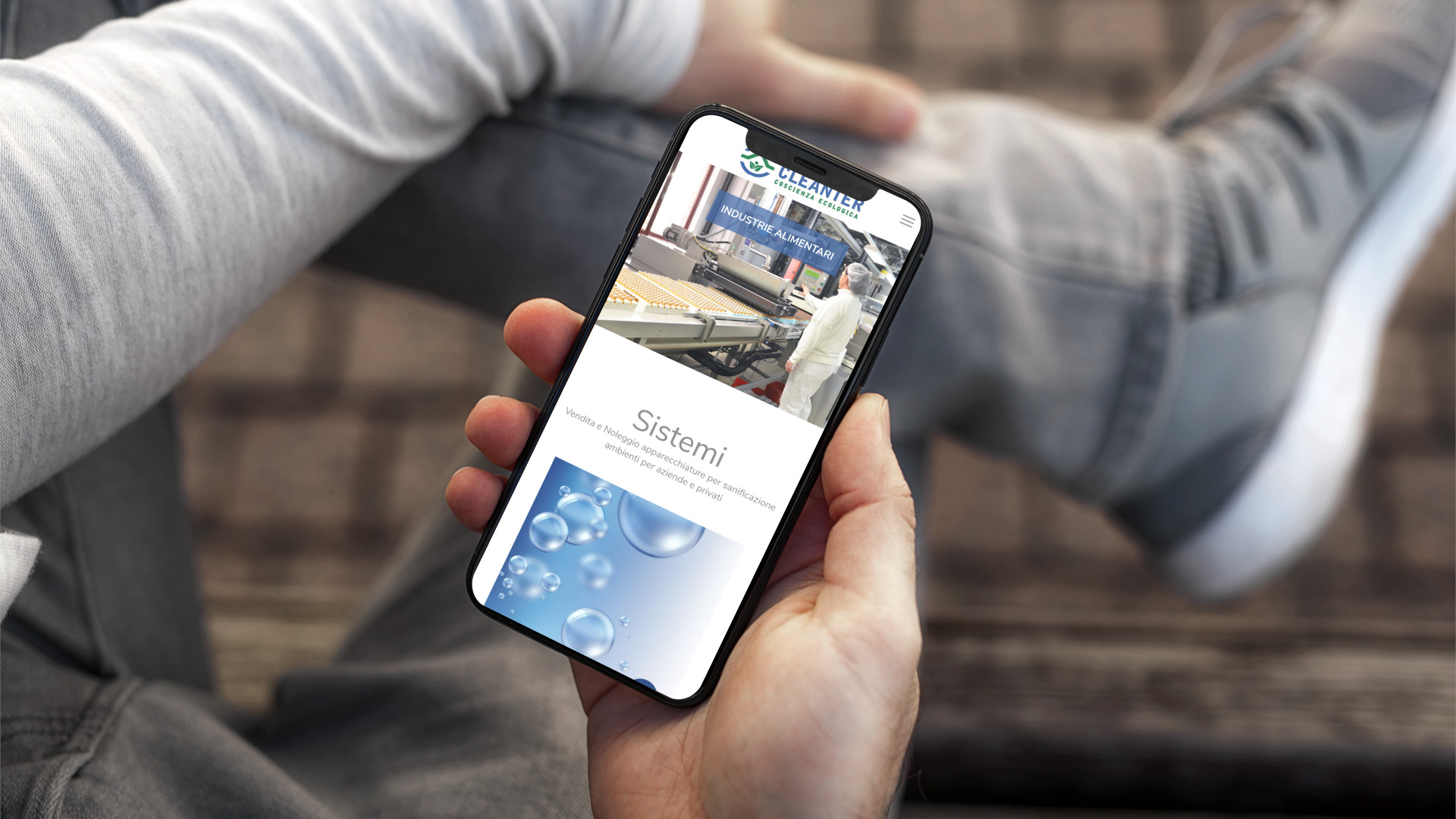 Mano con iPhone che mostra il sito web in modalità mobile responsive di Cleanter di Teramo