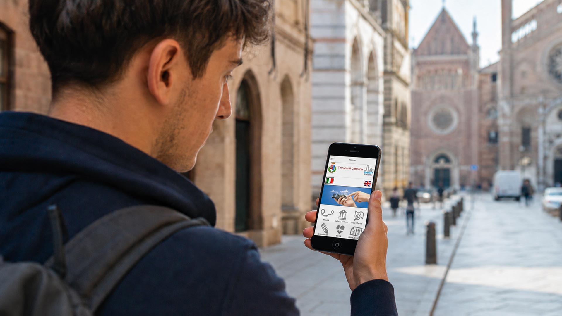Ragazzo in città con smartphone mentre guarda la Web App Comune di Cremona