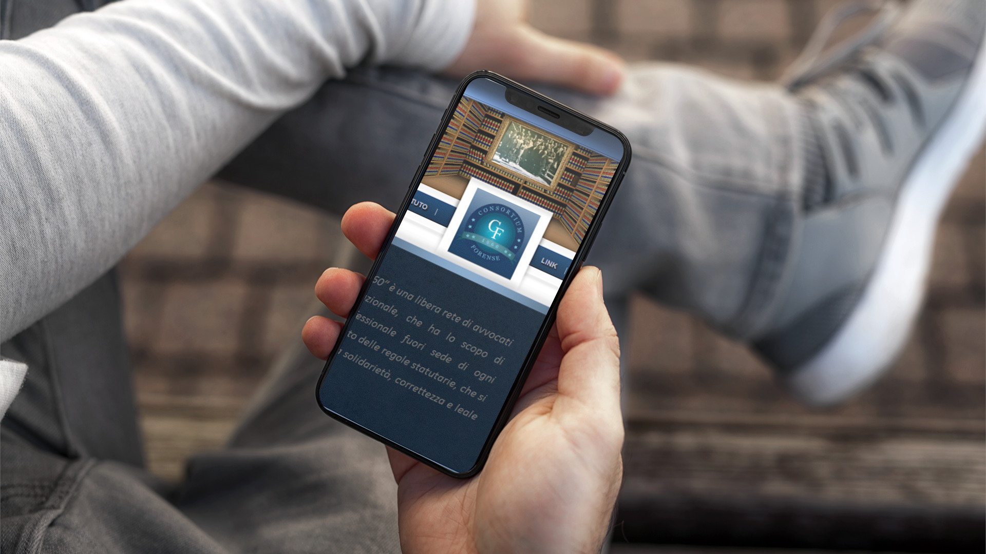 Mano con iPhone che mostra il sito web in modalità mobile responsive del Consortium Forense 1960 di Napoli