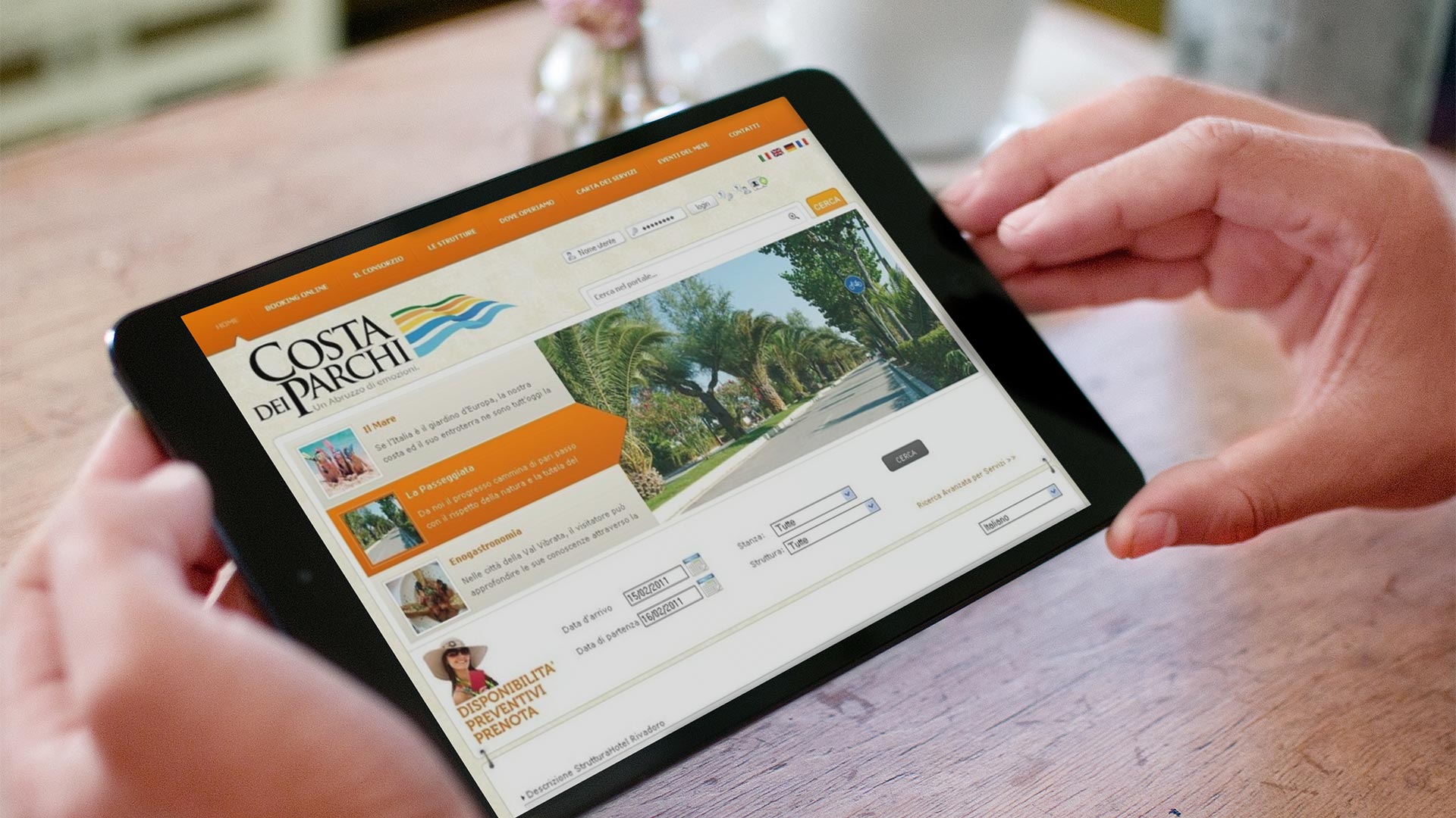 IPad mini nero in orizzontale su tavolo che mostra il portale turistico Costa dei Parchi