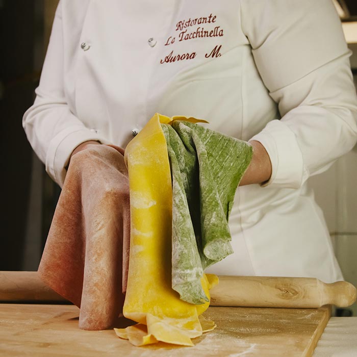Cuoca della Tacchinella prepara la sfoglia per la pasta all'uovo