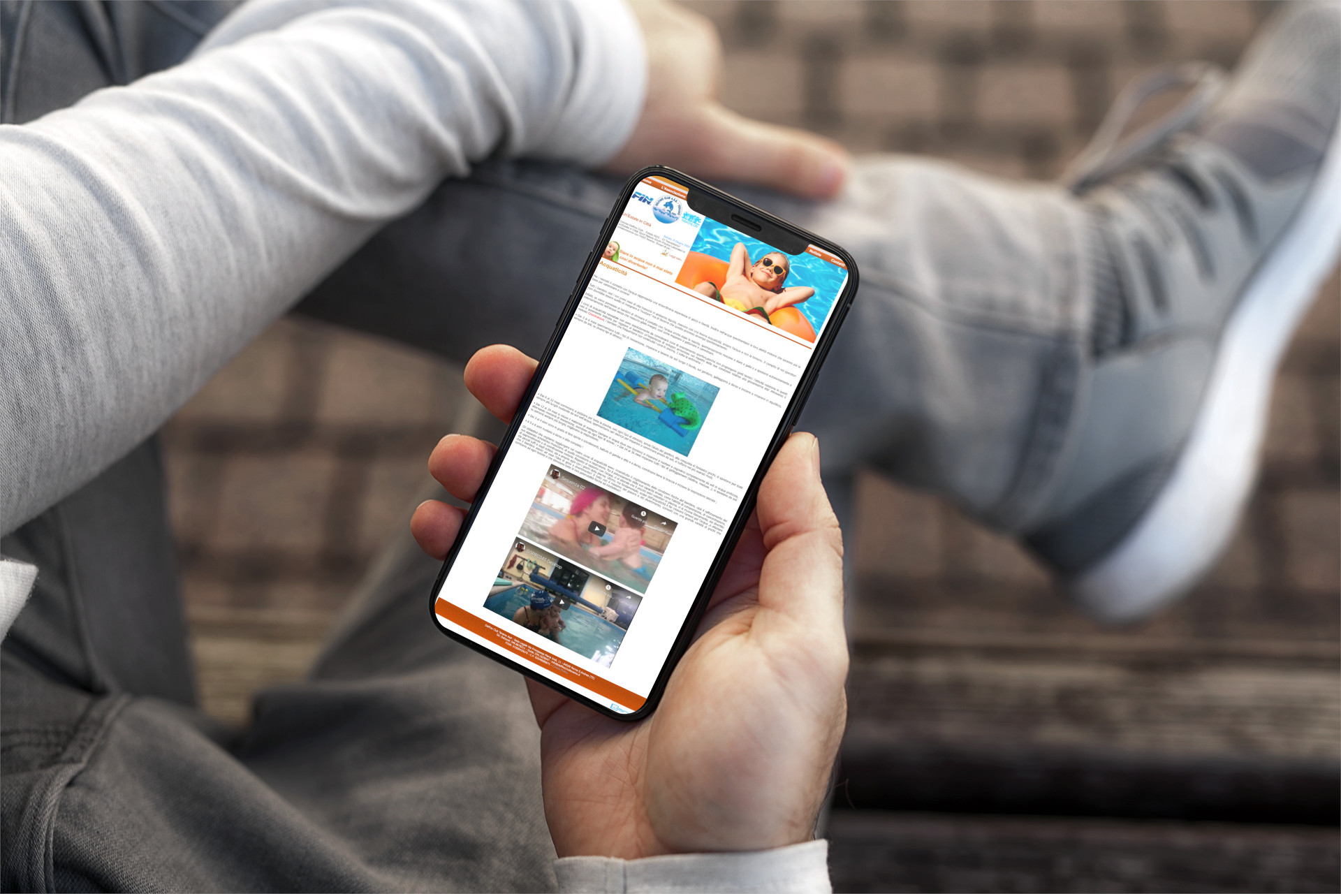 Mano con iPhone che mostra il sito web in modalità mobile responsive di Delfino Club Teramo