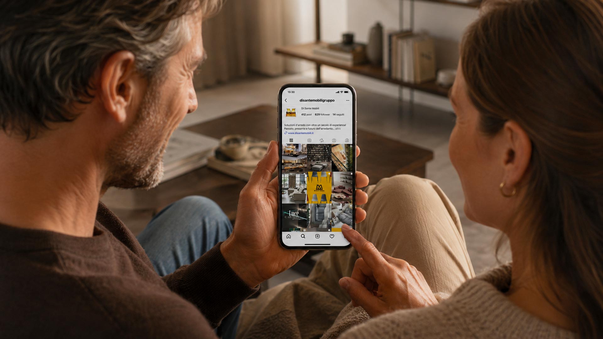 Coppia seduta in salotto mentre guarda Instagram Di Sante Mobili dal cellulare, gestione social