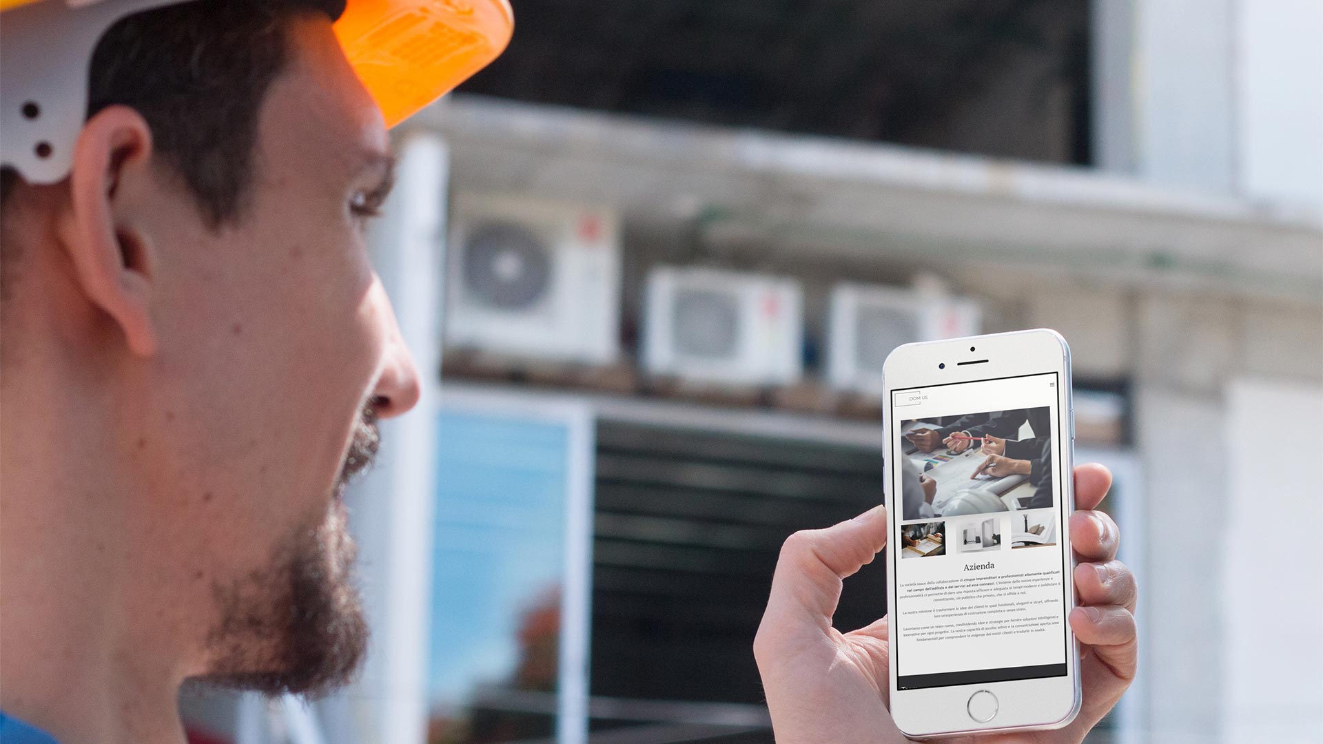 Ingegnere con caschetto arancione in cantiere che consulta il Sito Web DOM-US su smartphone