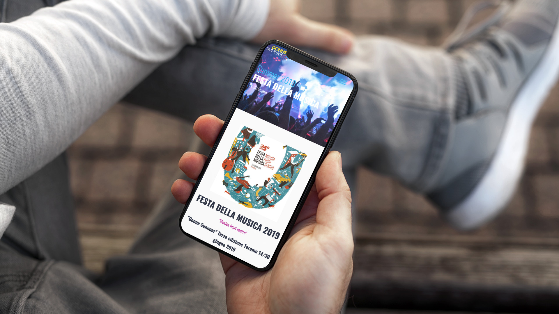 Mano con iPhone che mostra il sito web in modalità mobile responsive di Donne Summer di Teramo