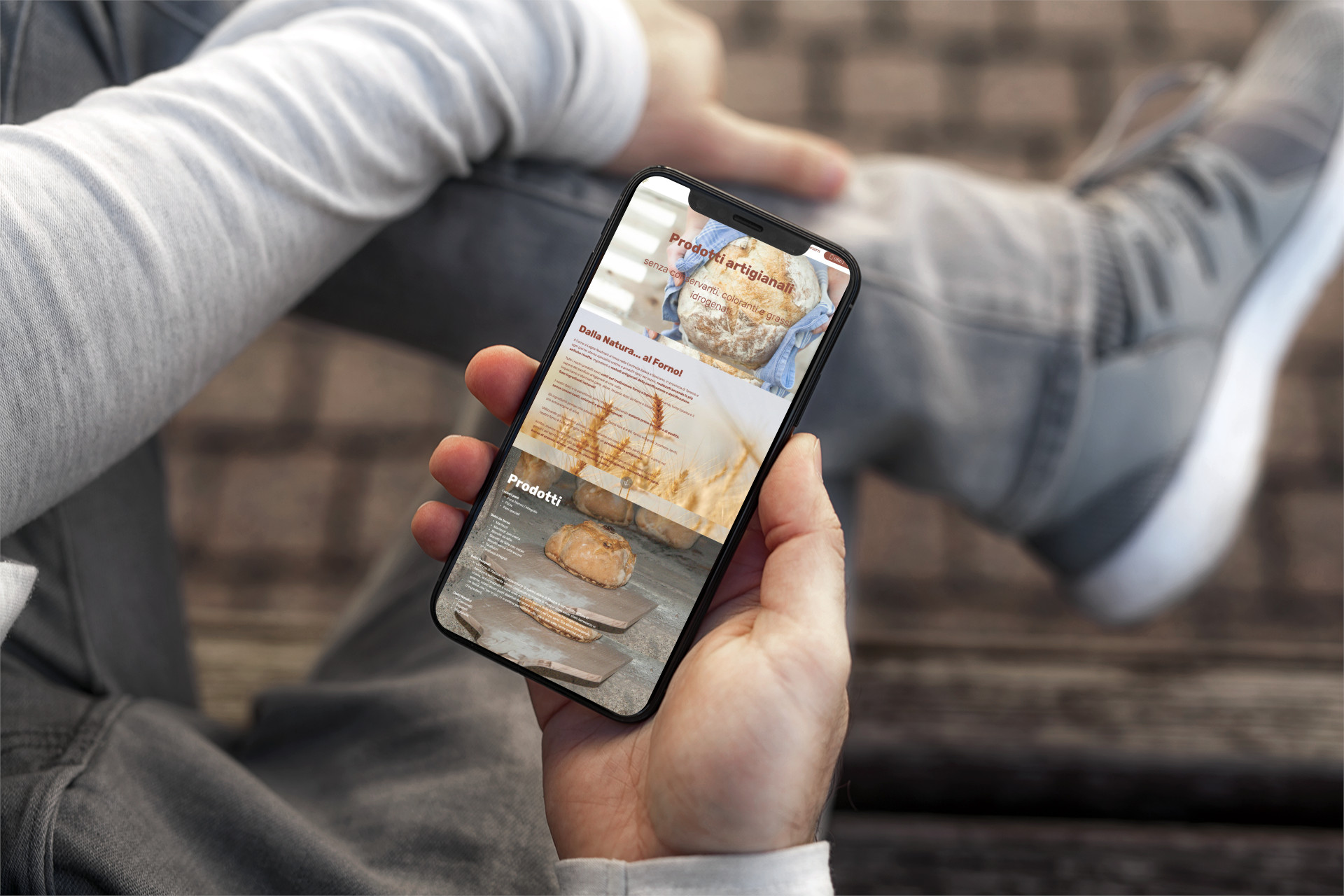 Mano con iPhone che mostra il sito web in modalità mobile responsive del Forno a Legna Nustriani di Basciano