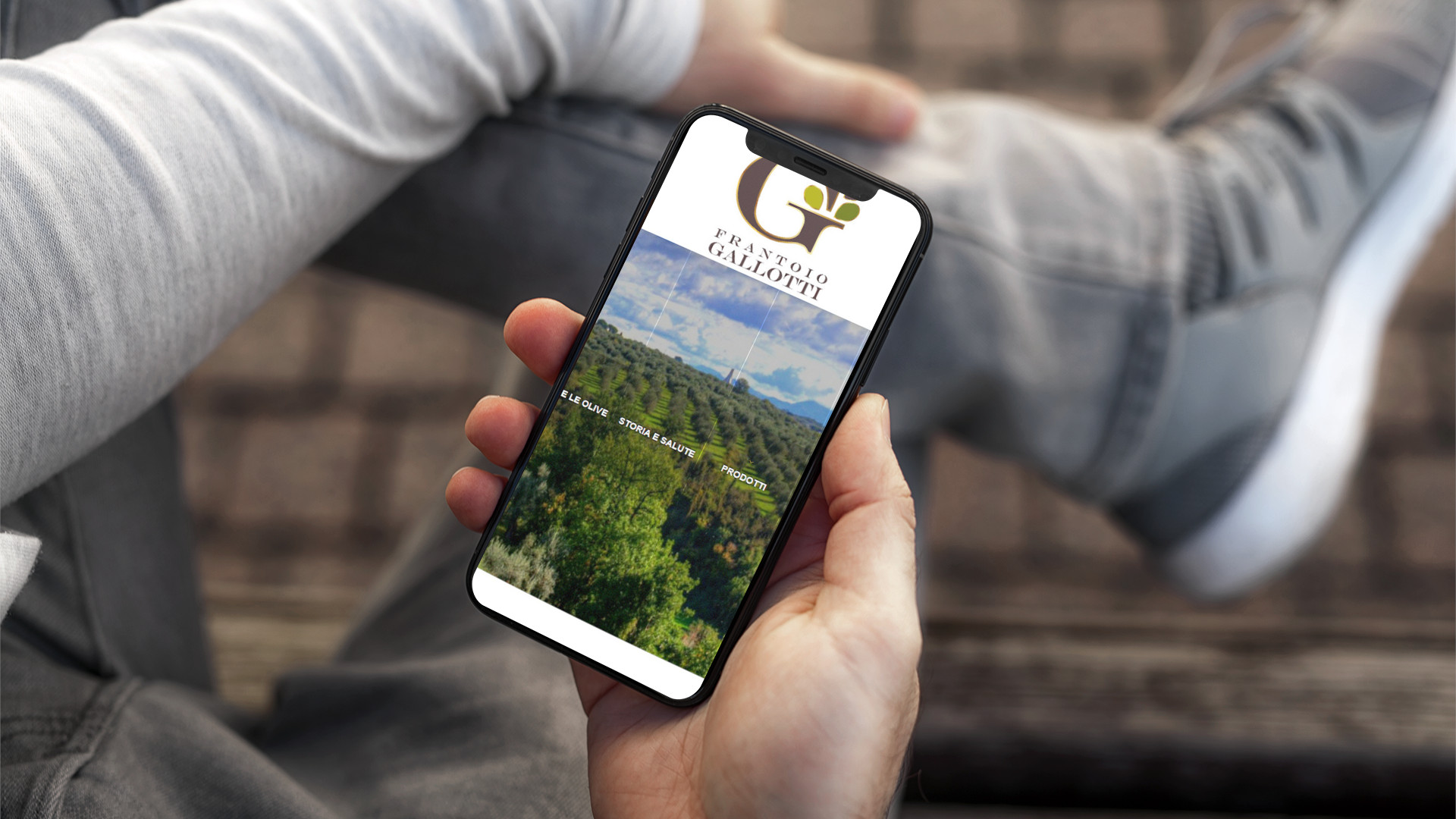 Mano con iPhone mostra il sito mobile del Frantoio Gallotti