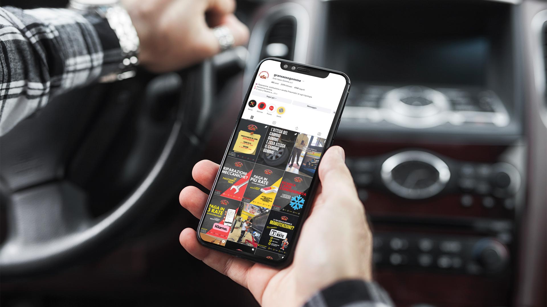 Uomo in auto con iPhone durante la visualizzazione dei contenuti Instagram di Gran Sasso Gomme