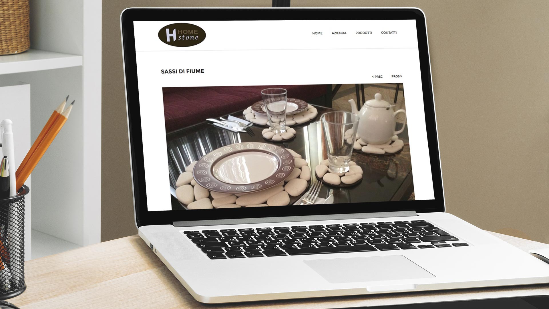 MacBook su scrivania da graphic designer che mostra il Sito Web Home Stone Italy