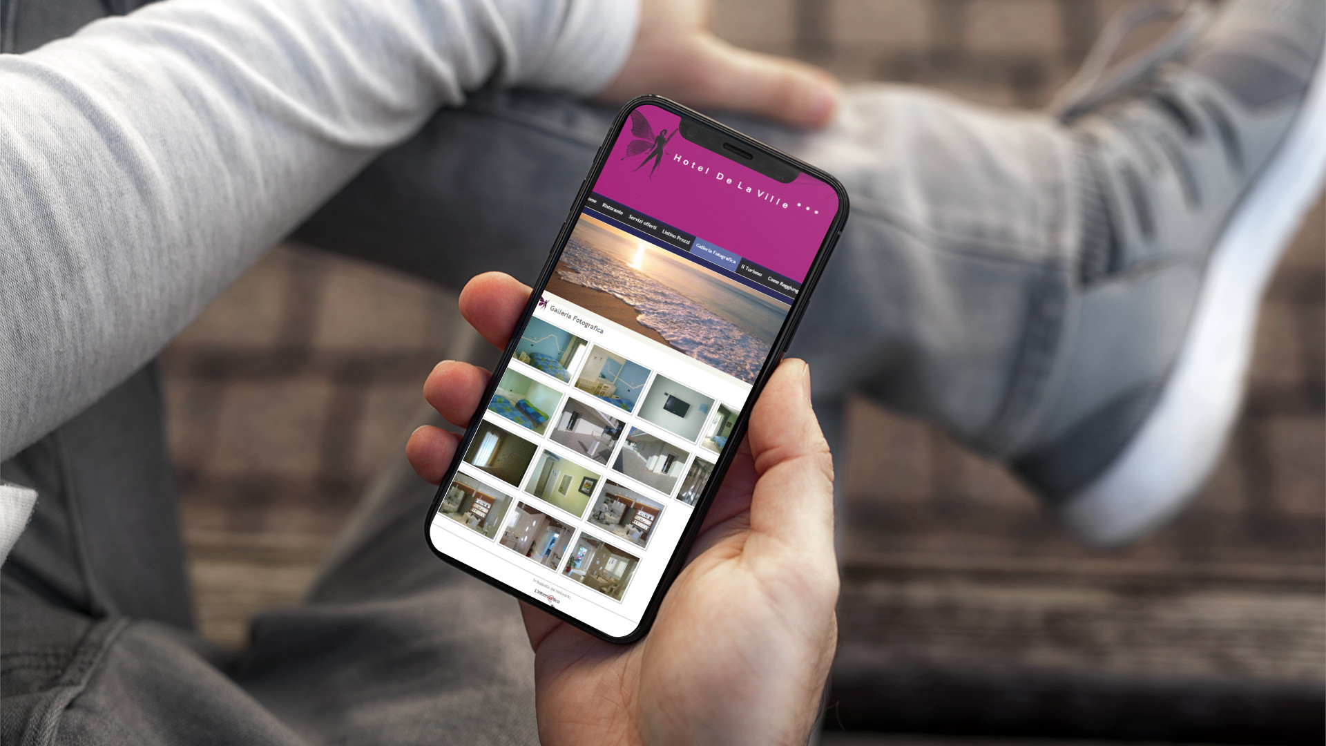 Mano con iPhone mostra il sito mobile dell'Hotel De La Ville