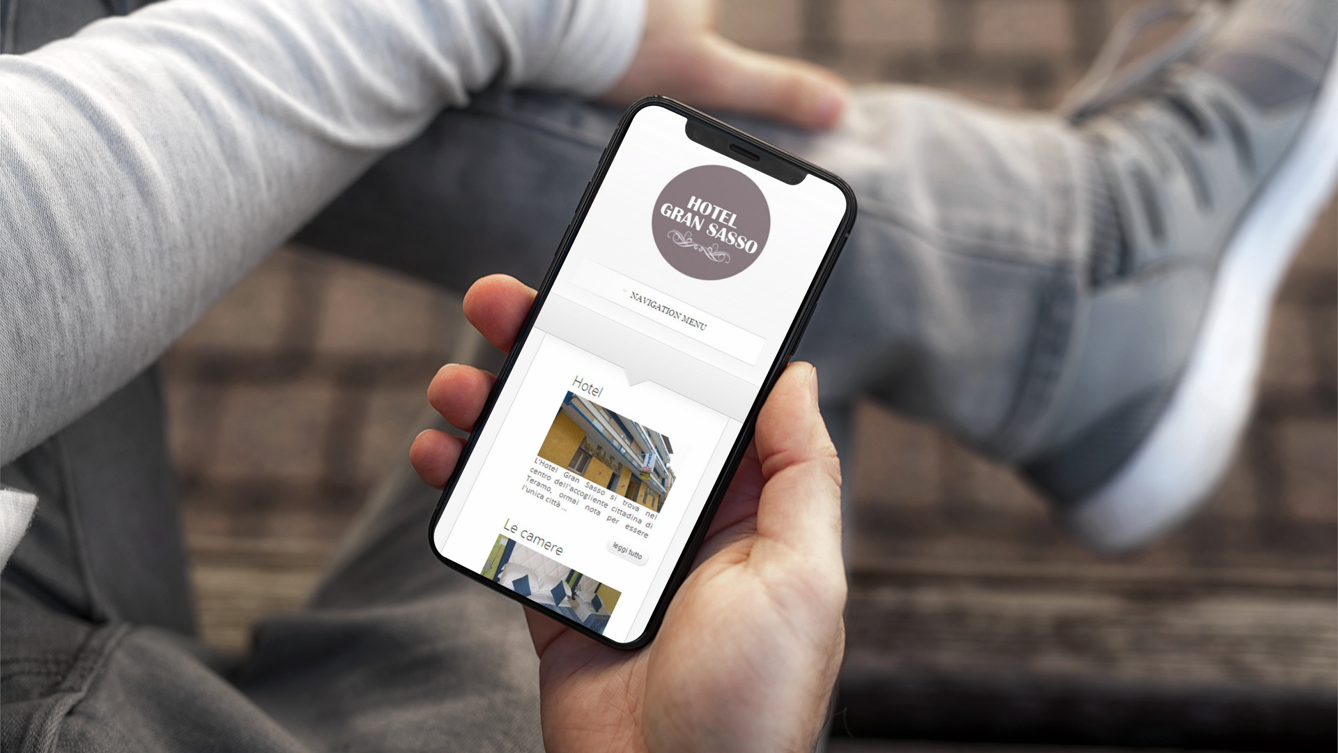 Mano con iPhone che mostra il Sito Web in modalità mobile responsive di Hotel Gran Sasso Teramo