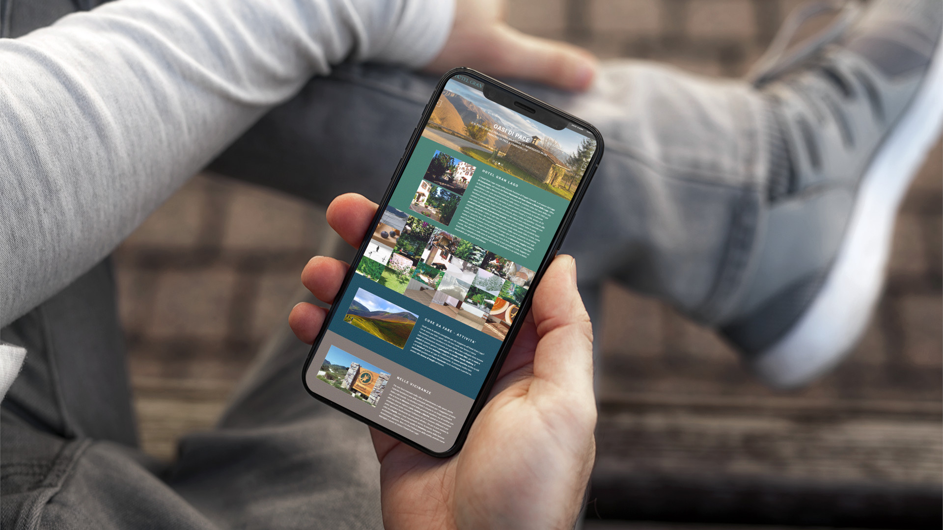 Mano con iPhone che mostra il sito web in modalità mobile responsive dell'Hotel Gran Lago di L'Aquila