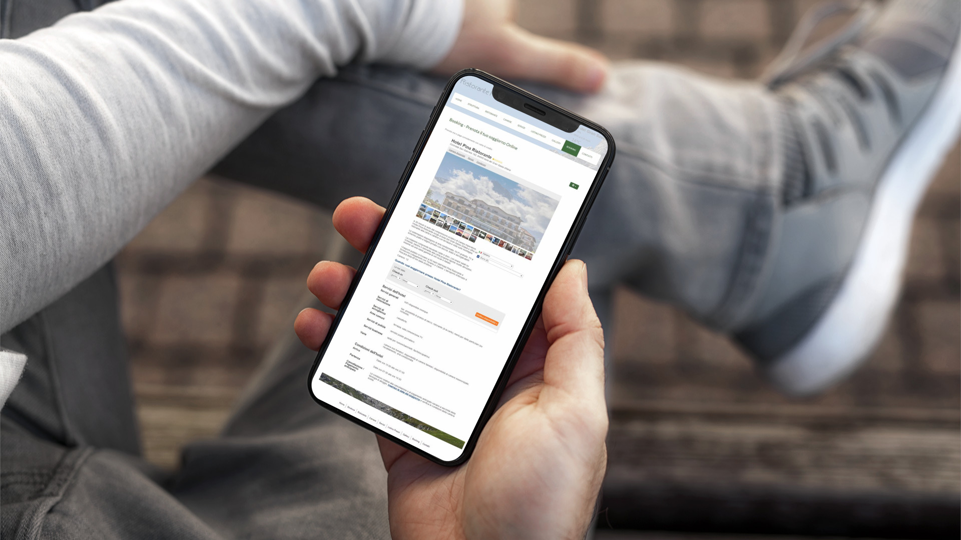 Mano con iPhone che mostra il sito web in modalità mobile responsive dell'Hotel Pina di Isola Del Gran Sasso