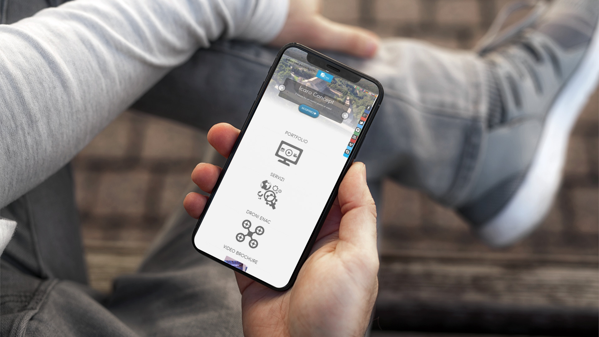 Mano con iPhone che mostra il sito web in modalità mobile responsive di Icaro Droni
