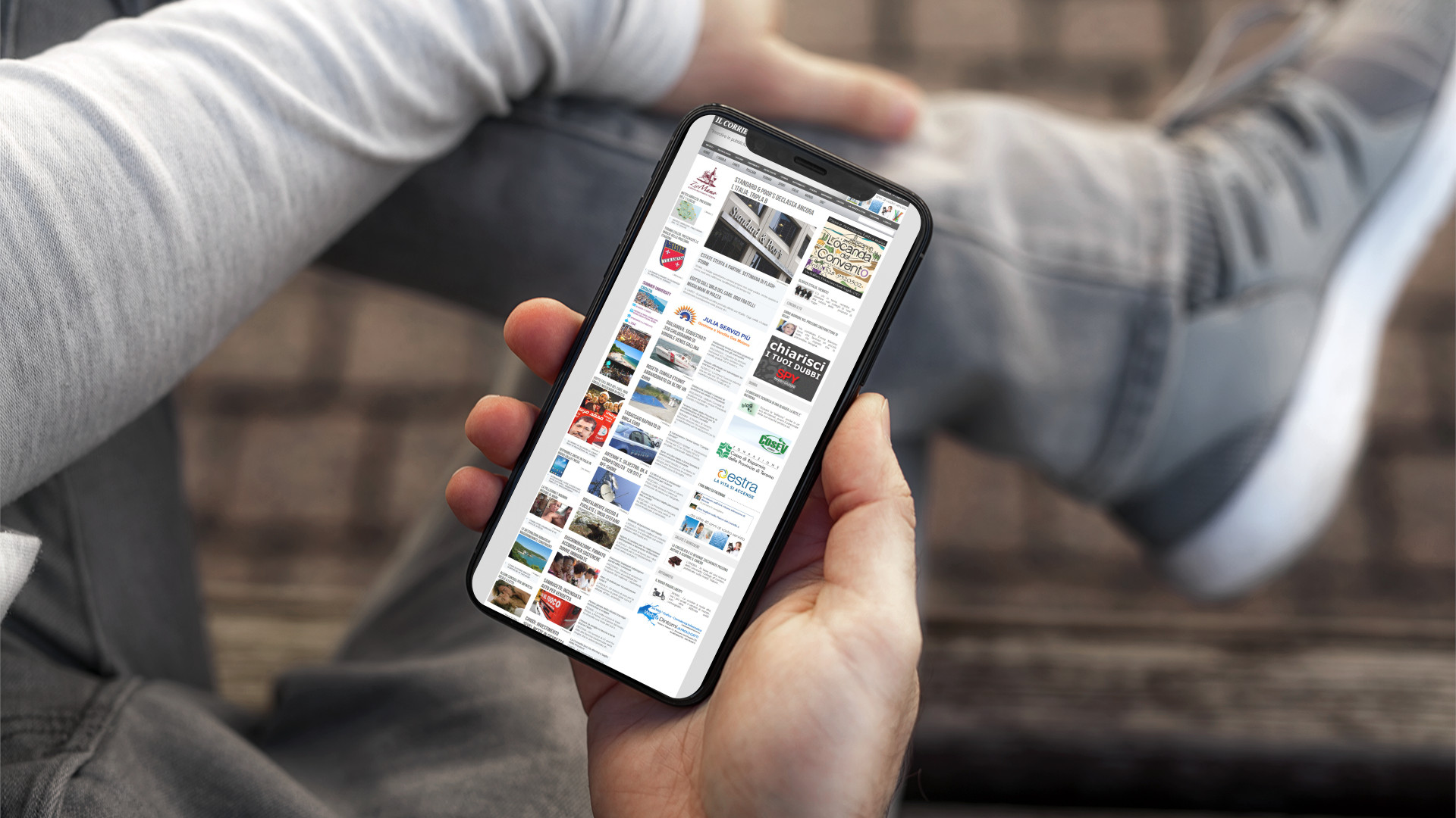 Mano con iPhone che mostra il sito web in modalità mobile responsive de Il Corriere D'Abruzzo a Teramo in Abruzzo