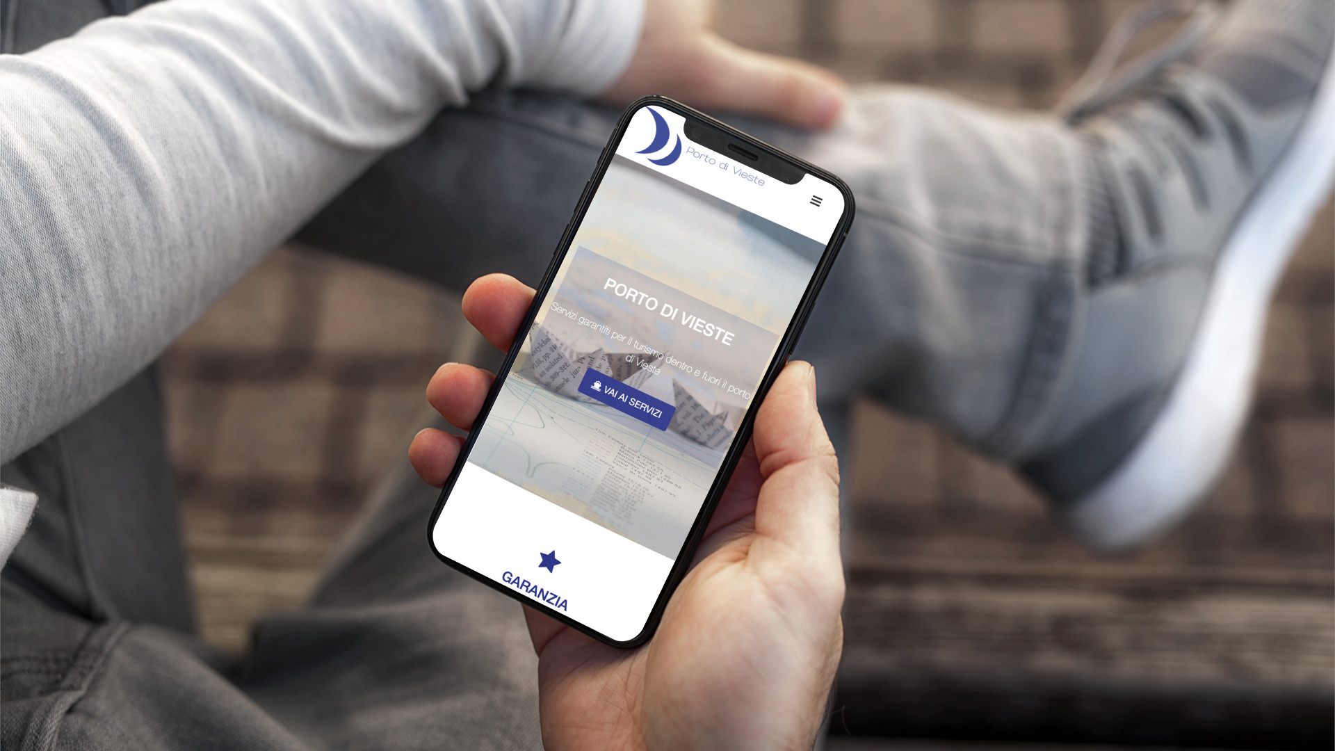 Mano con iPhone che mostra il sito web in modalità mobile responsive del Porto di Vieste