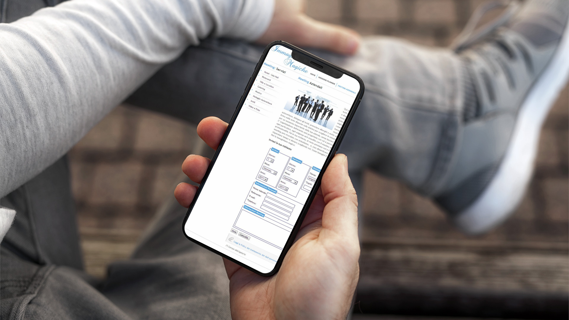 Mano con iPhone che mostra il sito web in modalità mobile responsive di Immagini Magiche di Teramo