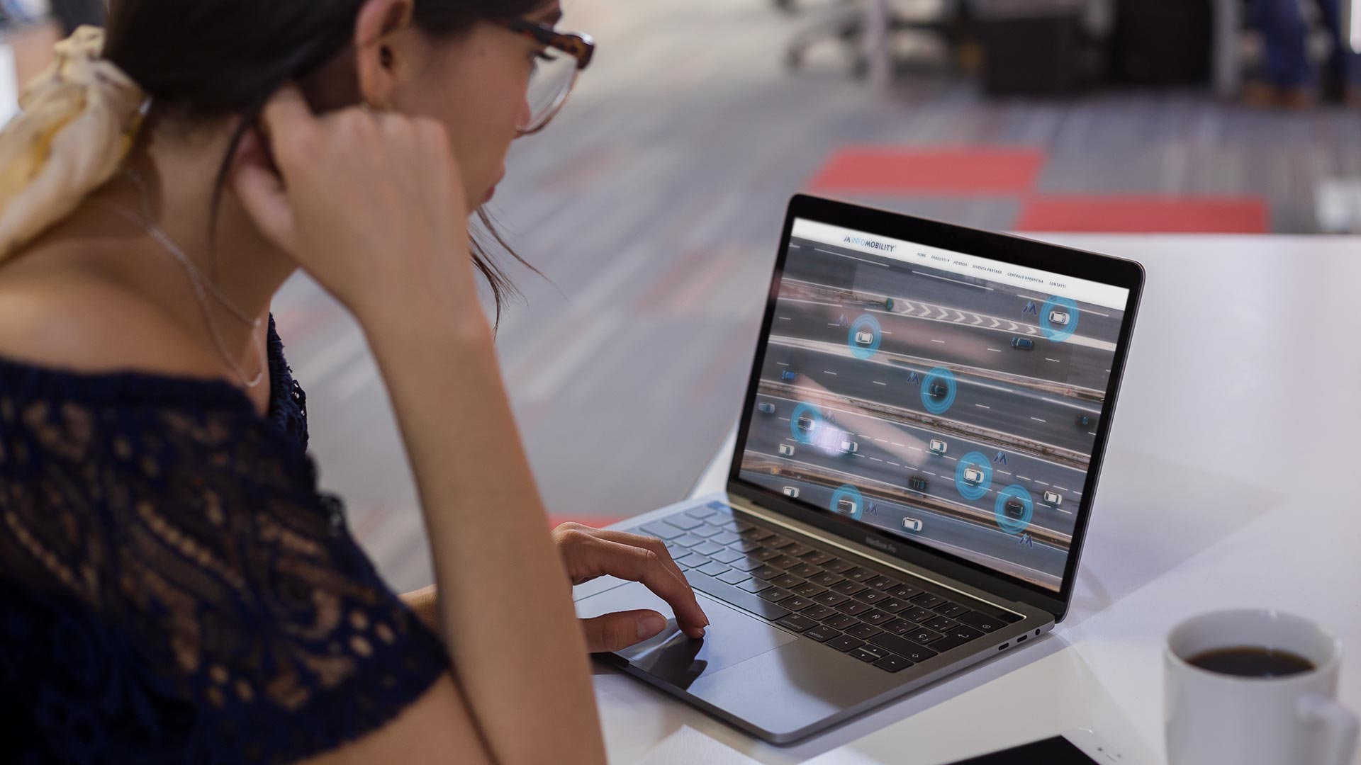 Ragazza al MacBook su scrivania usa il Sito Web Infomobility