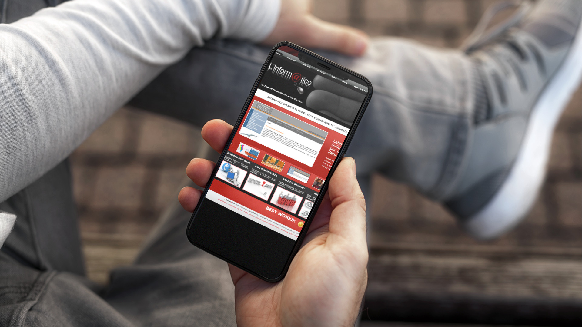 Mano con iPhone che mostra il sito web in modalità mobile responsive dell'Informatico di Teramo