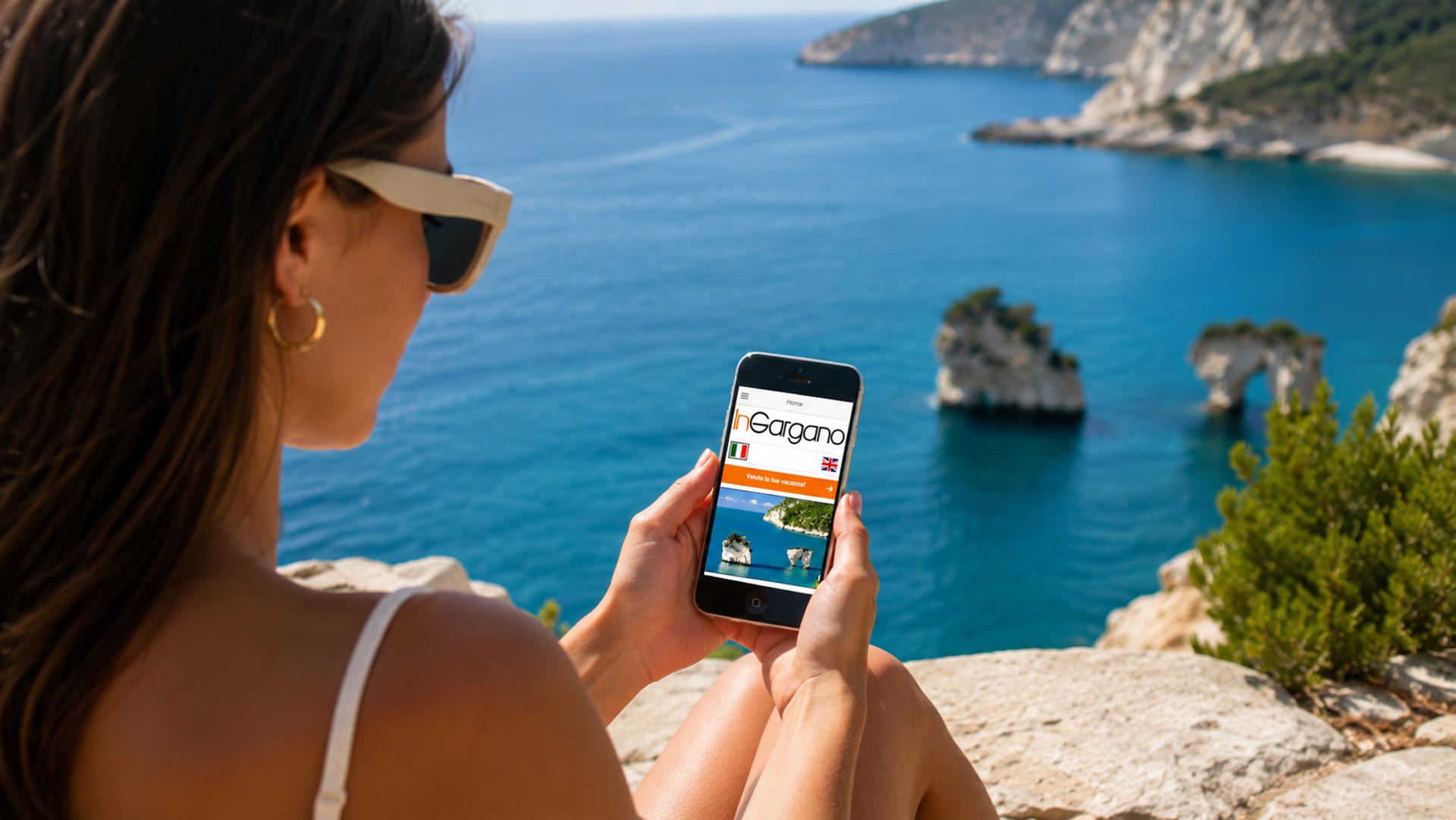 Ragazza al mare con smartphone mentre guarda l'App InGargano Portale Turistico Gargano