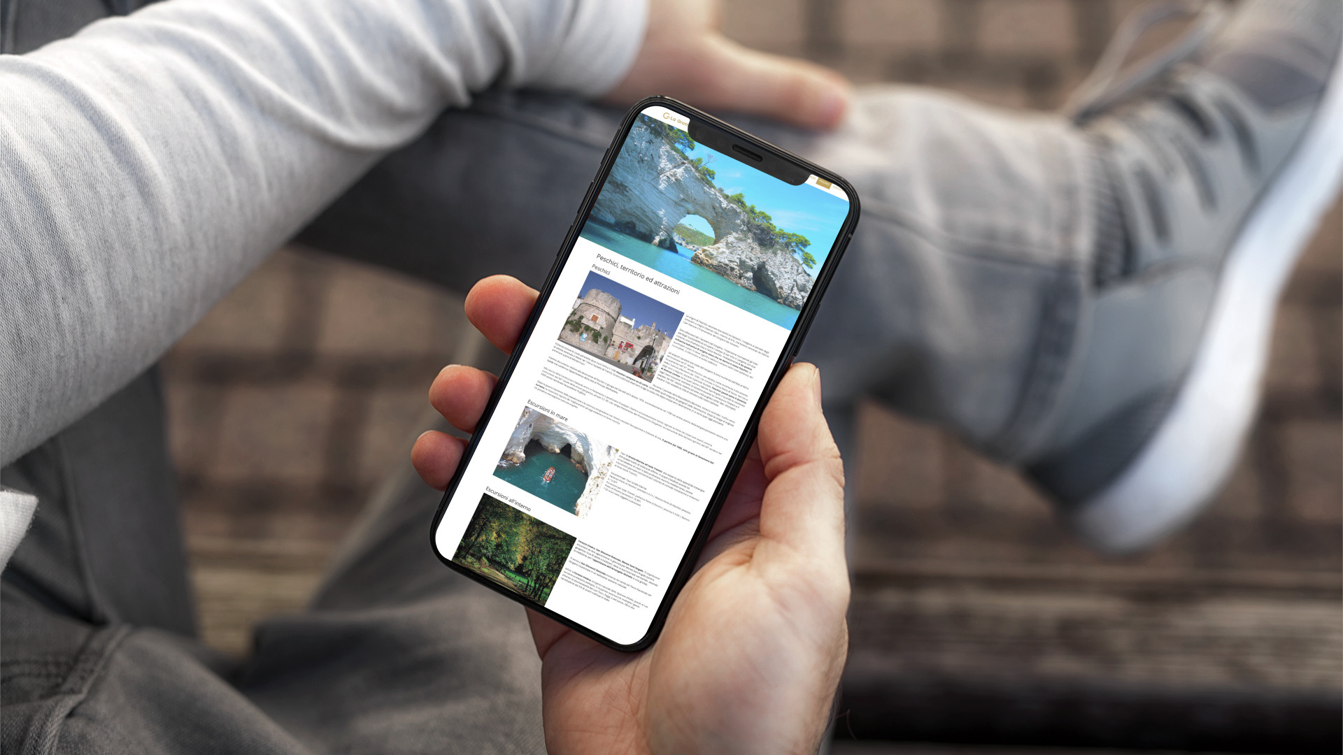 Mano con iPhone che mostra il sito web in modalità mobile responsive del sito web de La Grotta Peschici