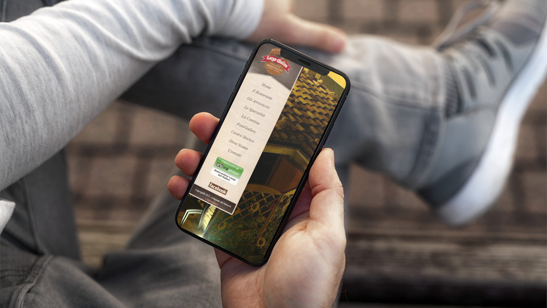 Mano con iPhone che mostra il sito web in modalità mobile responsive del Largo Del Mulino di Teramo