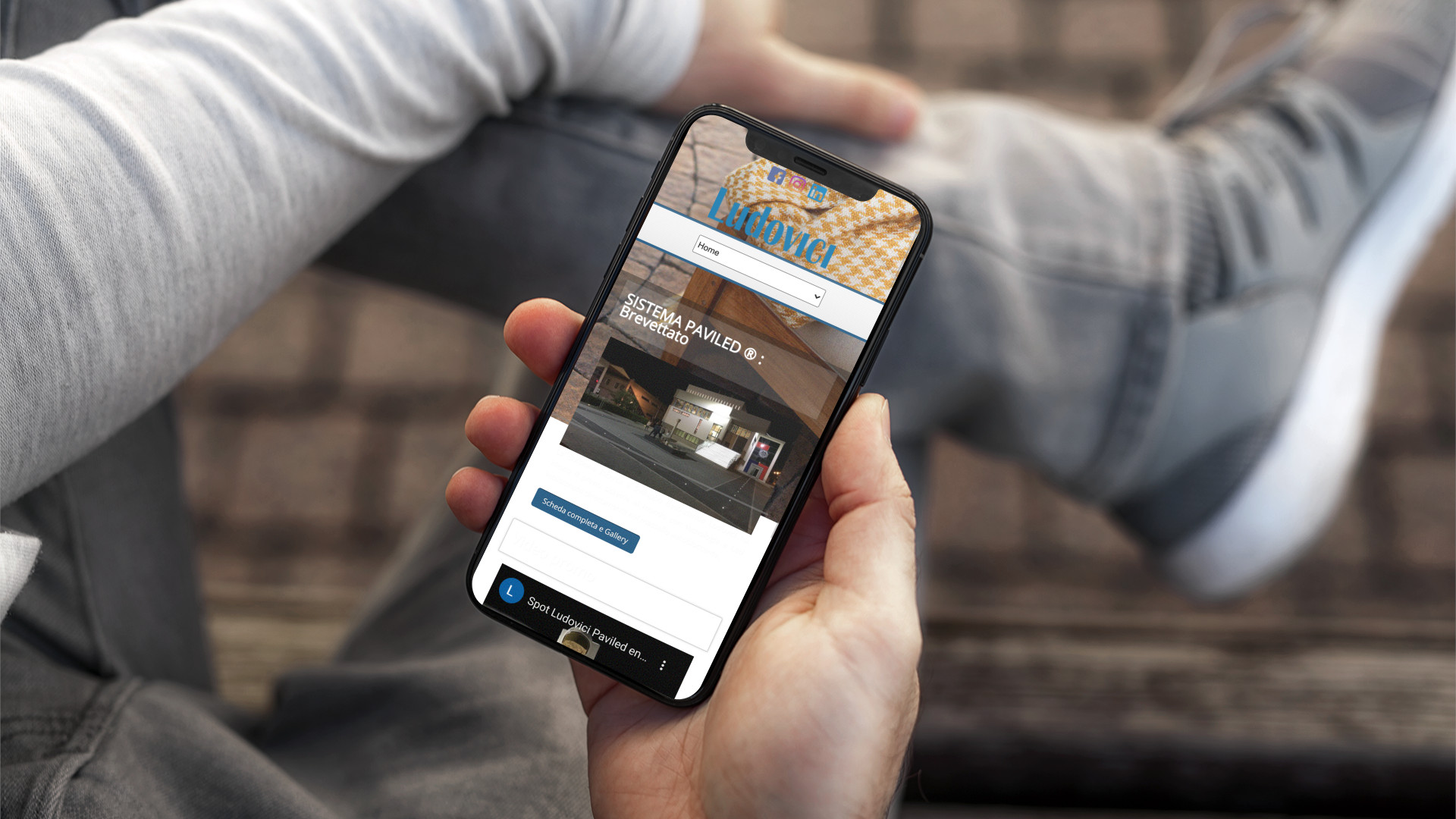 Mano con iPhone che mostra il sito web in modalità mobile responsive di Ludovici