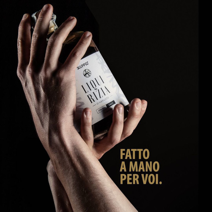 Mani che avvolgono una bottiglia di Ratafià Scuppoz per Instagram