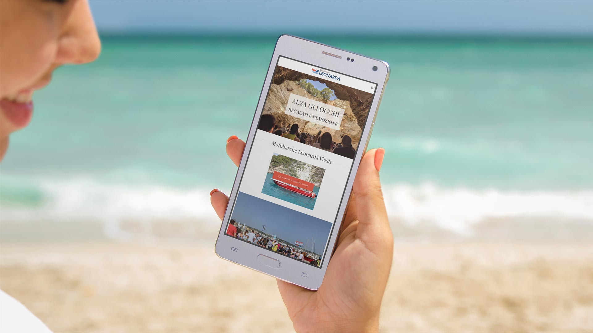 Ragazza in spiaggia guarda da smartphone il Sito Web MBLeonardaVieste.it