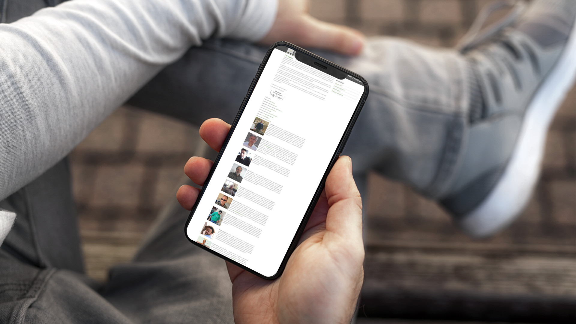 Mano con iPhone che mostra il sito web in modalità mobile responsive di Meccanici Terrestri