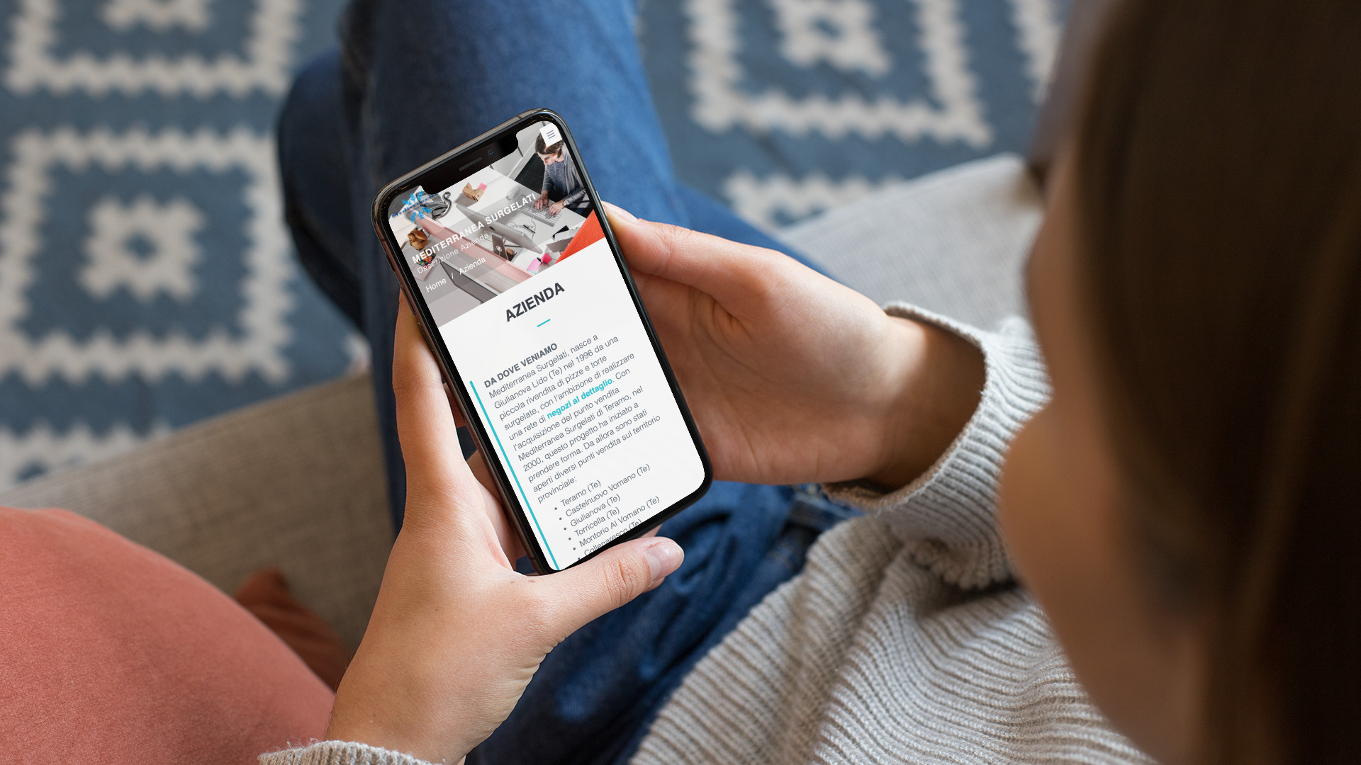 Mano con iPhone che mostra il sito web in modalità mobile responsive di Mediterranea Surgelati di Teramo