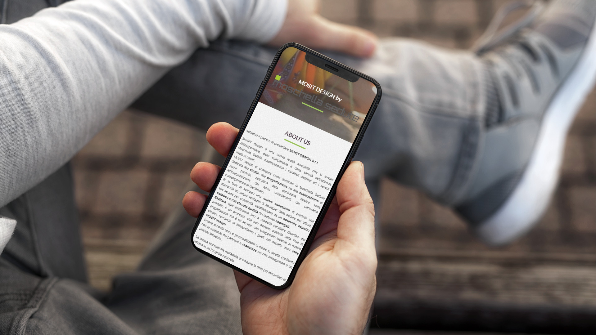 Mano con iPhone che mostra il sito web in modalità mobile responsive di Mosit Design di Teramo