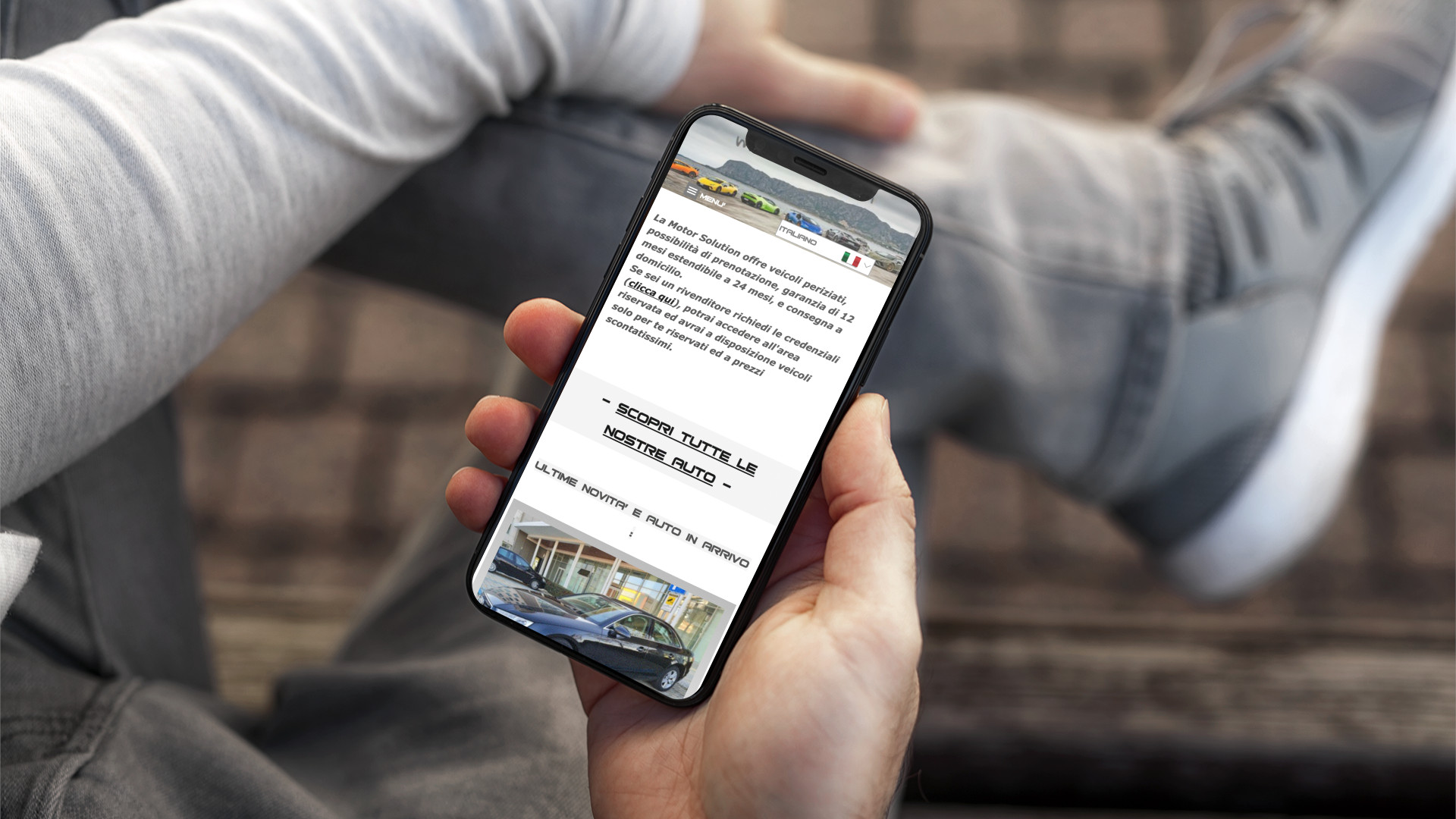 Mano con iPhone mostra il sito mobile di Motor Solution