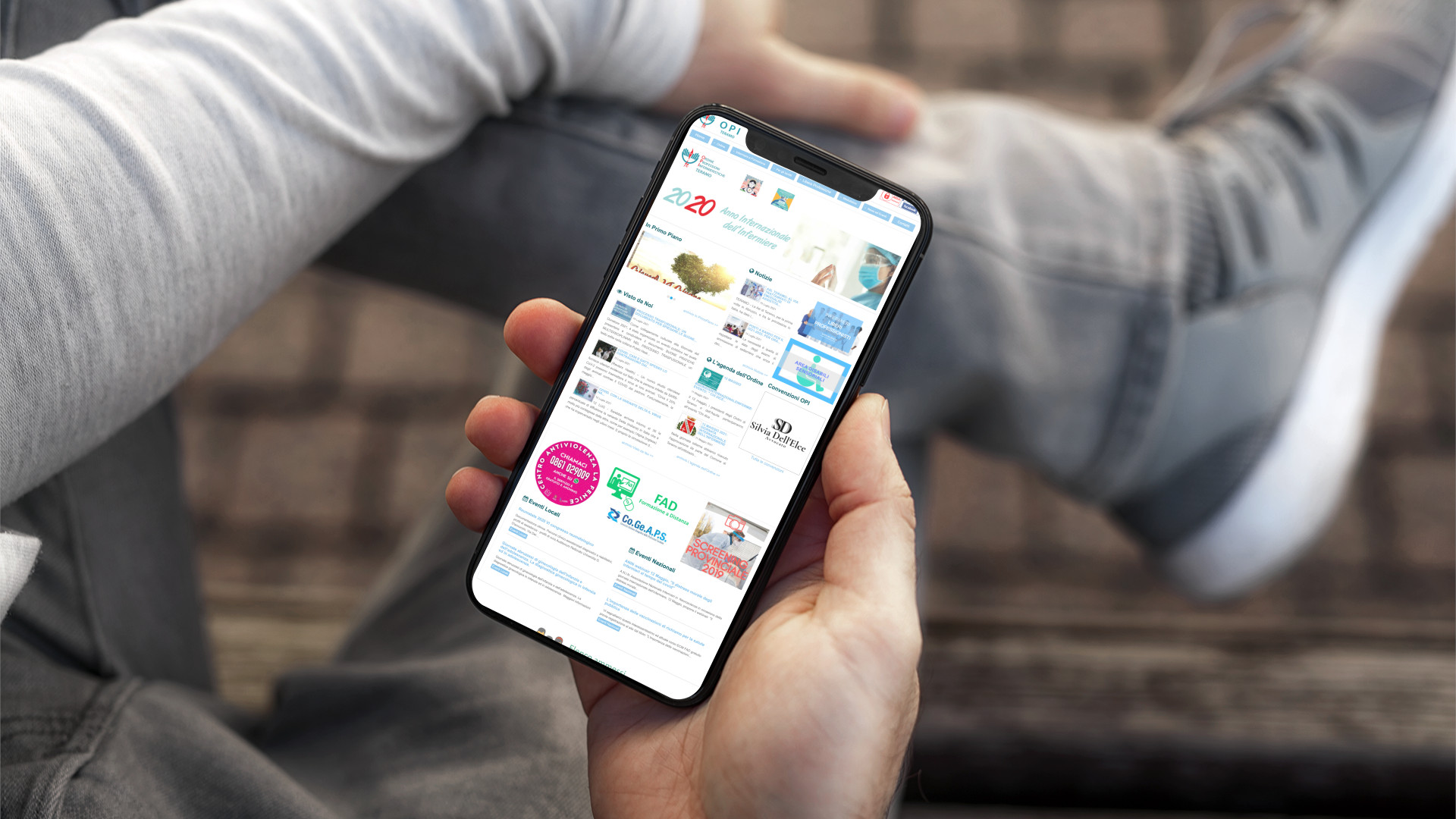 Mano con iPhone che mostra il sito web in modalità mobile responsive della OPI Teramo