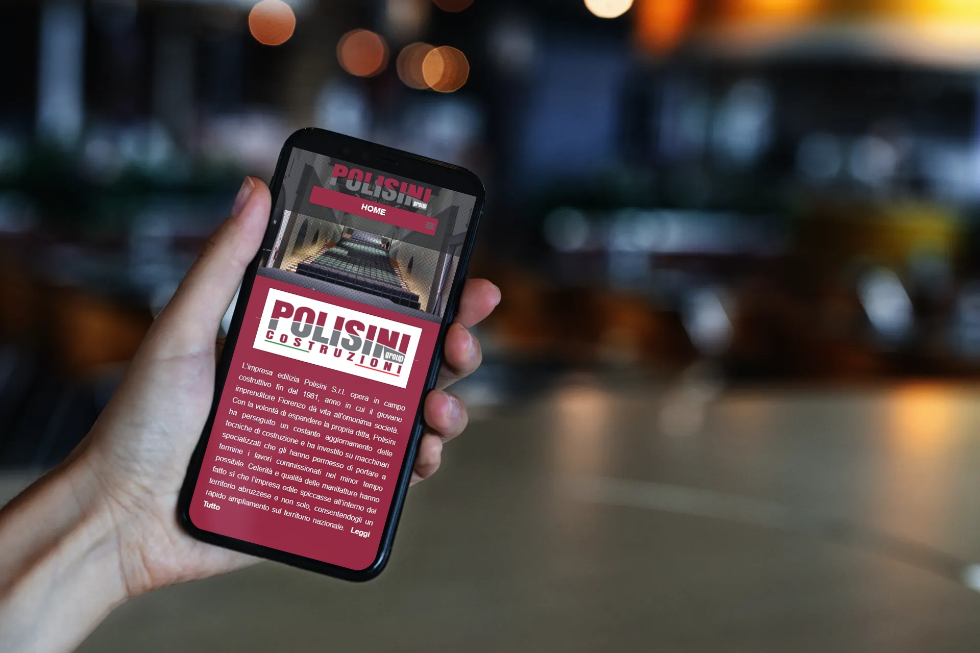 Ragazza designer in ristorante che visualizza il sito web responsive di Polisini Group in versione mobile