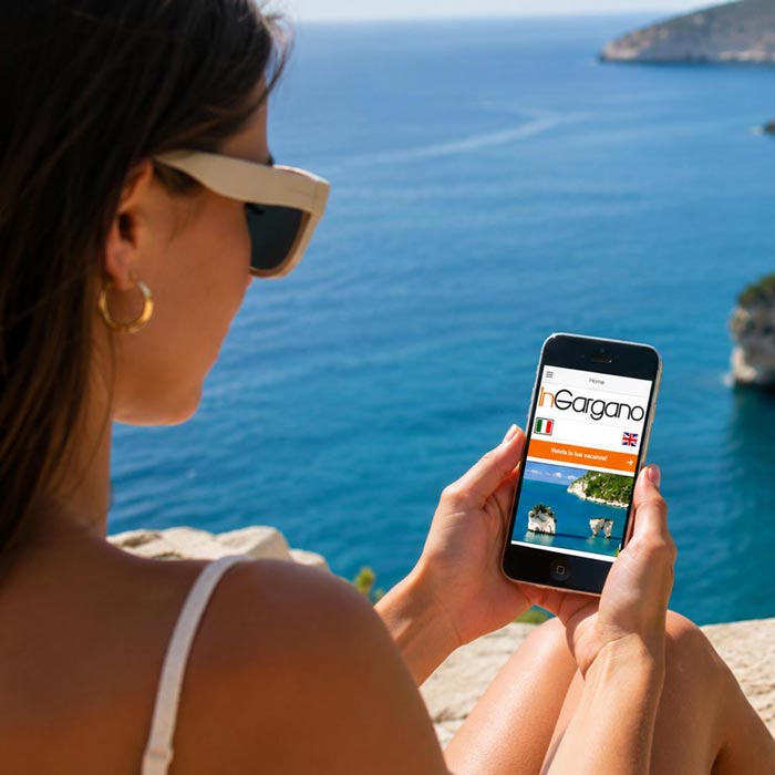 Ragazza al mare mentre consulta l'App InGargano, portale turistico del Gargano