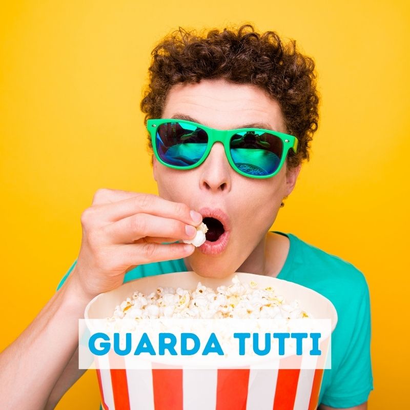 Ragazzo divertente mangia pop corn con occhiali da sole guarda nello schermo