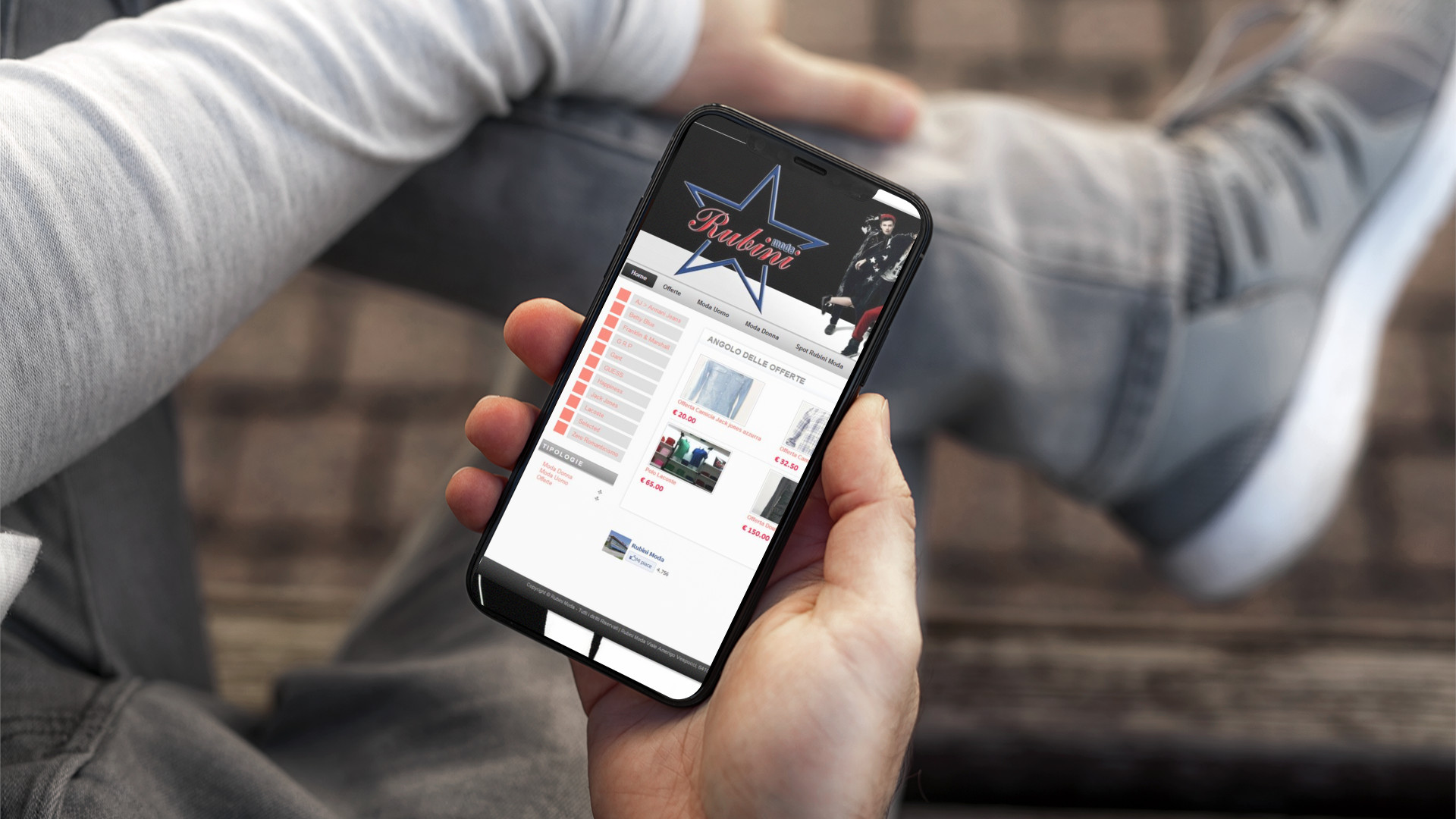 Mano con iPhone che mostra il sito web in modalità mobile responsive di Rubini Moda di Teramo
